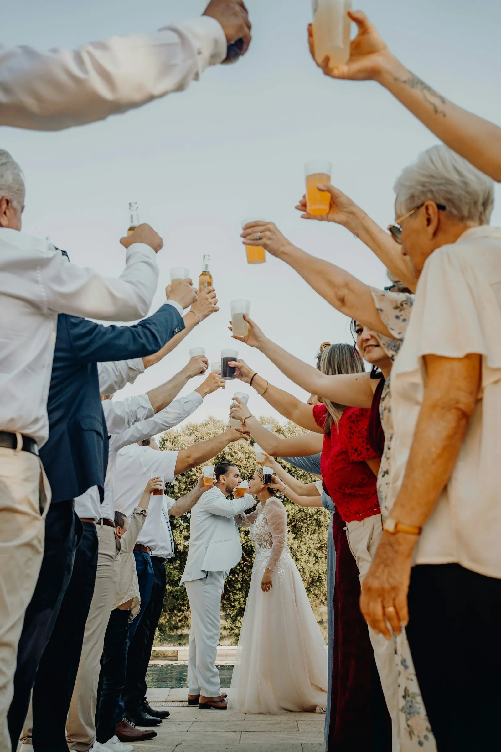 Guests raising glasses in an arch over the couple