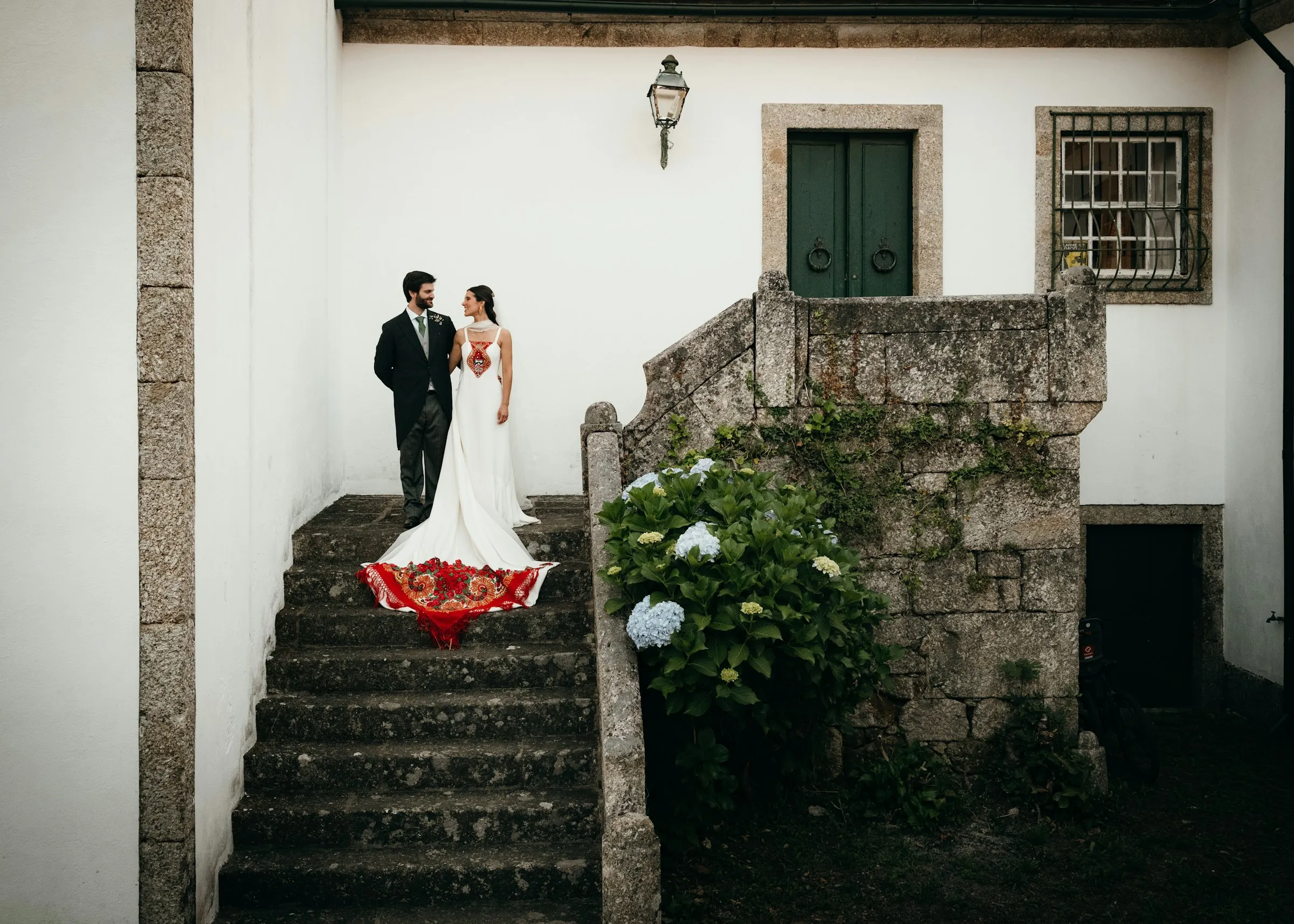 Beatriz and Henrique on the stone steps of the family house, a red shawl at their feet