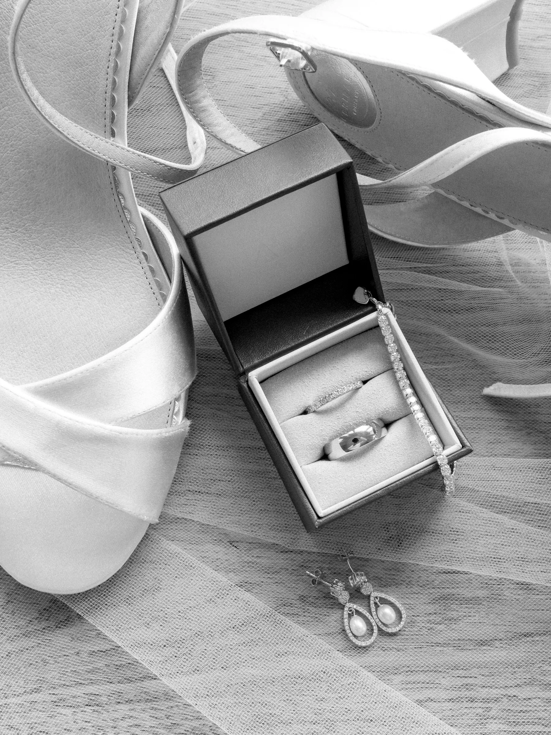 Wedding rings in a box beside satin shoes