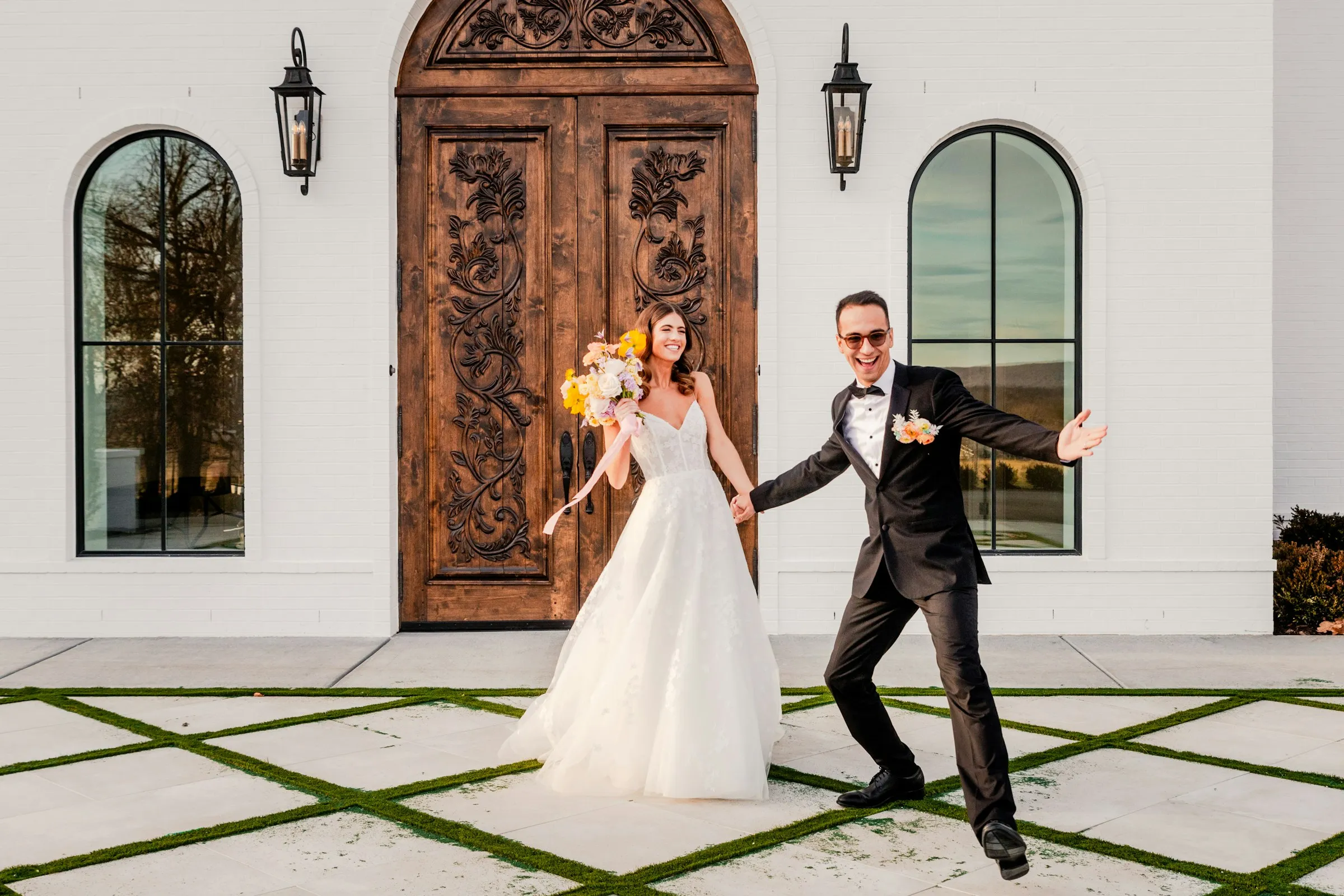 Clara and Duarte in front of carved wooden doors, Duarte dancing