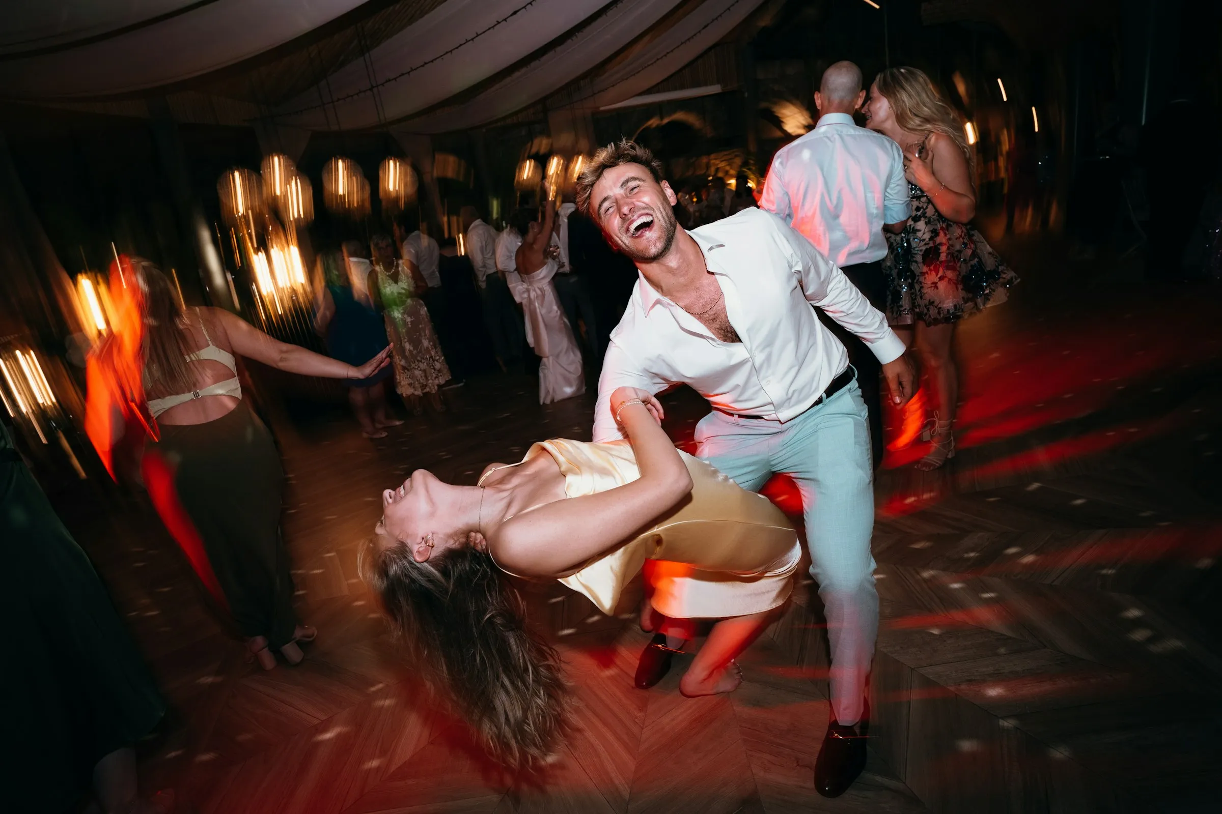 A guest dipped mid-dance under red party lights