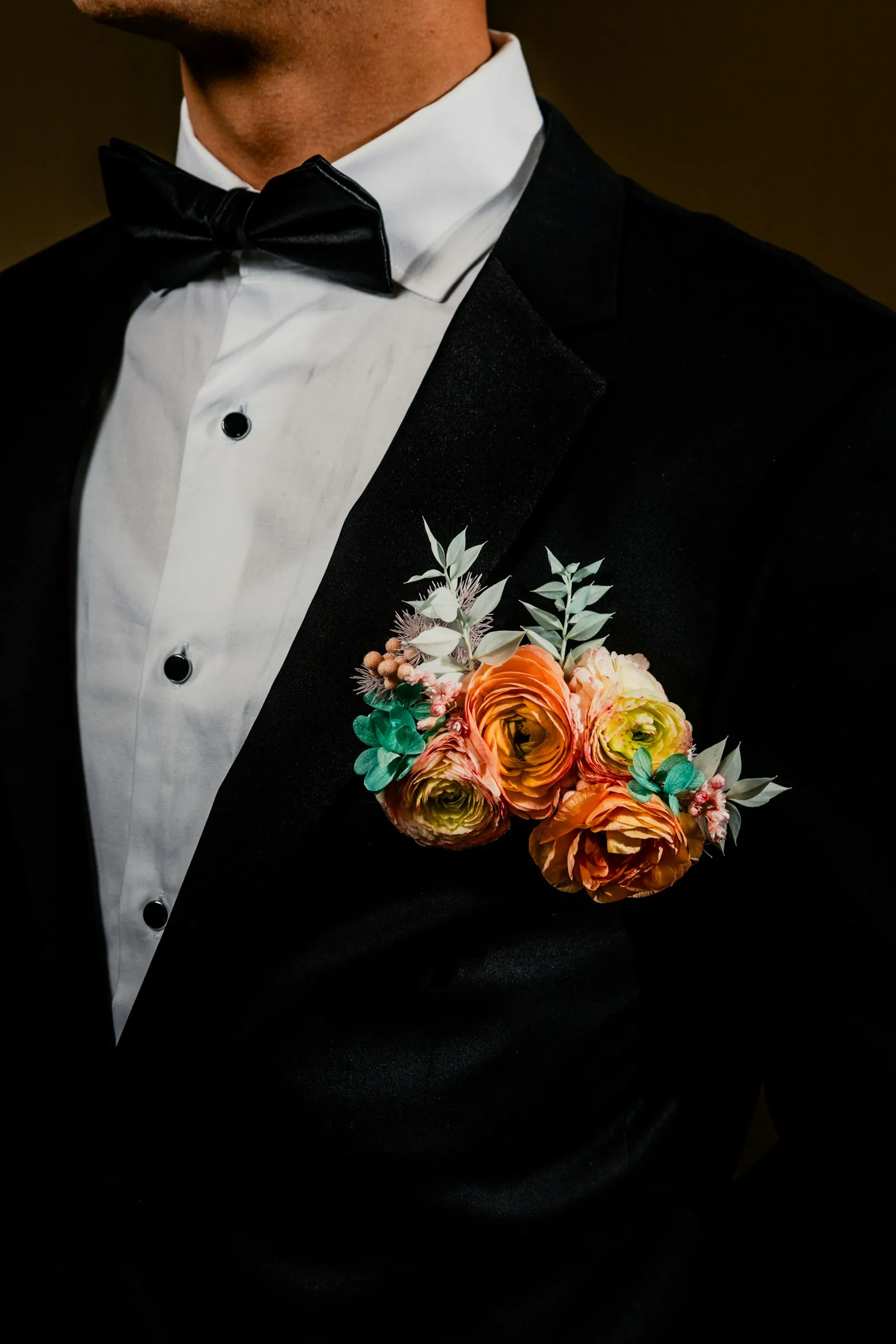 A boutonniere of orange flowers on a black tuxedo