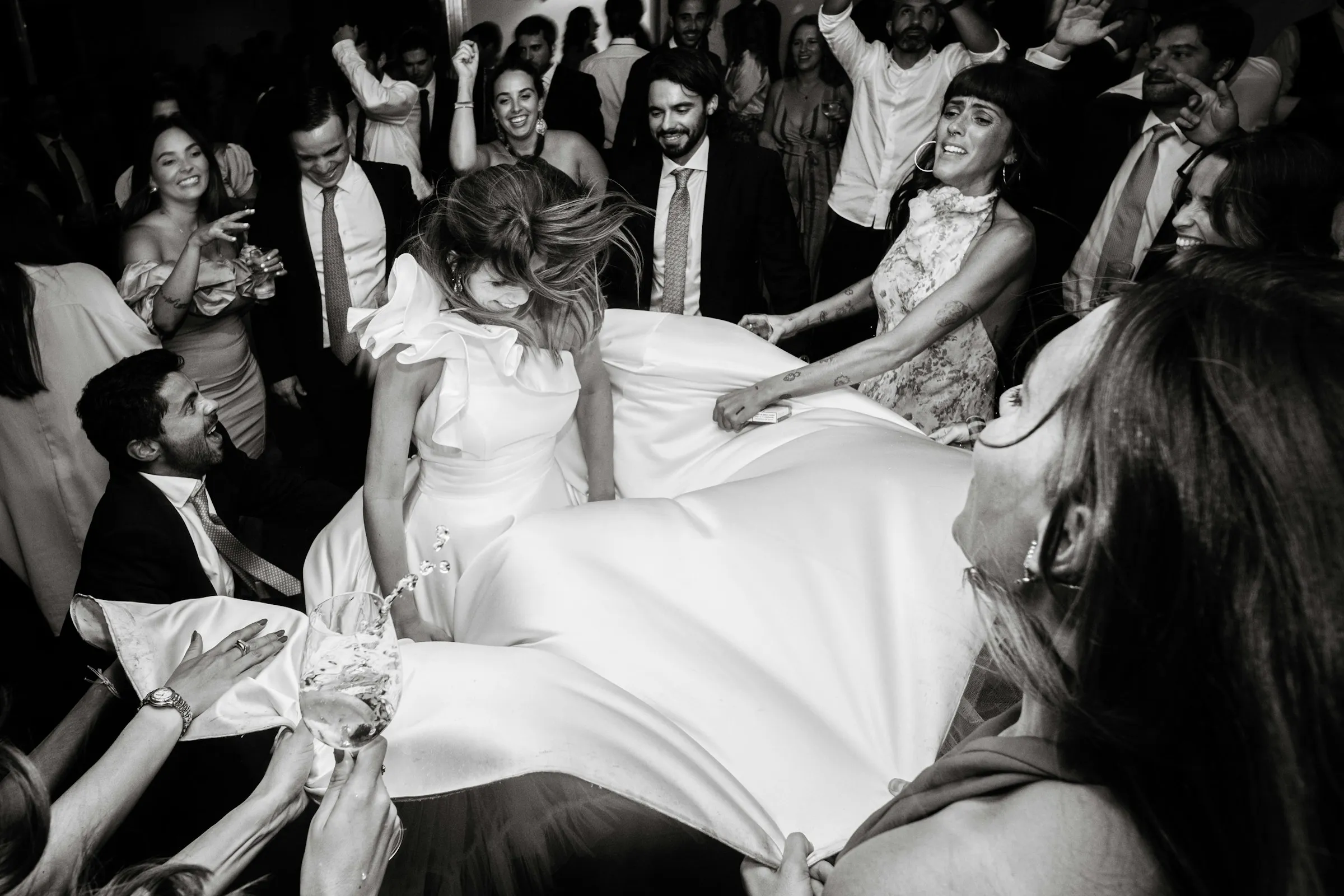 Black and white photograph of the bride surrounded by dancing friends